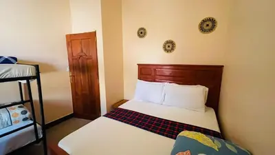 a small bedroom with a bed and a wooden headboard at Safari Roots Hostel in Arusha