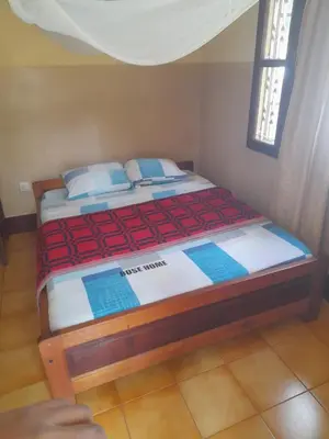 a bedroom with a bed with a red and white blanket at Rose Home in Moshi