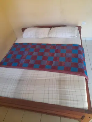 a bed with a checkered blanket on it at Rose Home in Moshi