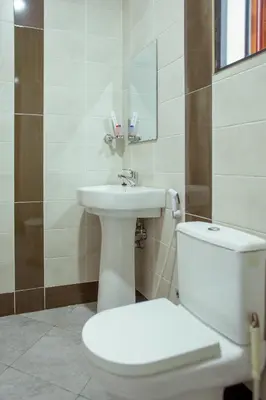 a bathroom with a white toilet and a sink at Sarnah Apartments in Arusha