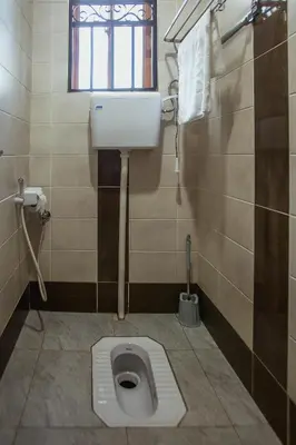a bathroom with a toilet in a stall with a window at Sarnah Apartments in Arusha