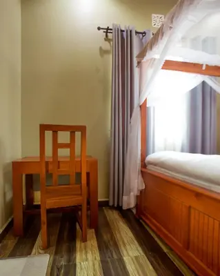 a bedroom with a desk and a bed and a chair at Sarnah Apartments in Arusha