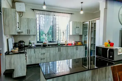 a kitchen with wooden cabinets and a microwave at Bellevie Homestay in Uru
