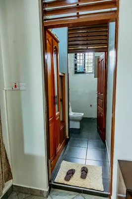 a bathroom with a toilet and a pair of sandals on the floor at Bellevie Homestay in Uru
