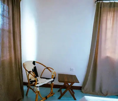 a chair and a wooden table in a room at Garden Villa 5BR Home Near Road,Nature and City Life in Arusha