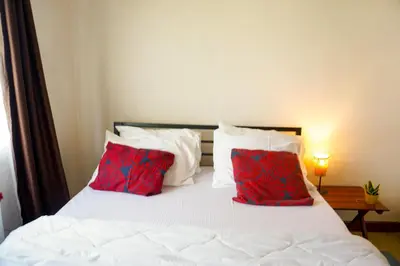 a bedroom with a white bed with red pillows at Garden Villa 5BR Home Near Road,Nature and City Life in Arusha