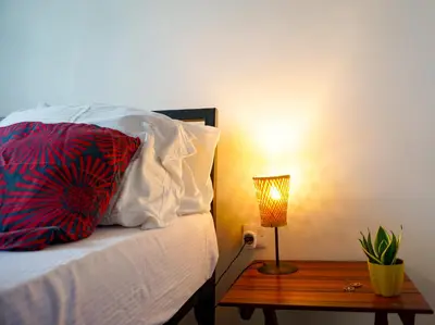 a bed with a pillow and a table with a lamp at Garden Villa 5BR Home Near Road,Nature and City Life in Arusha