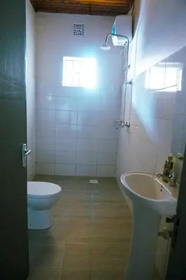 a bathroom with a sink and a toilet and a window at Garden Villa 5BR Home Near Road,Nature and City Life in Arusha