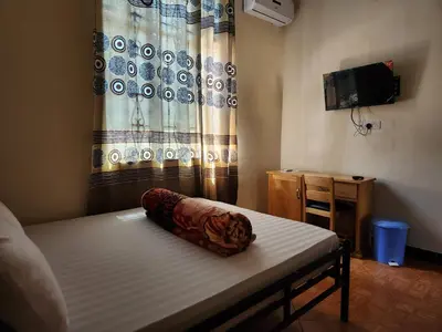 a small room with a bed and a curtain at Garden Inn Eco Stay in Msaranga