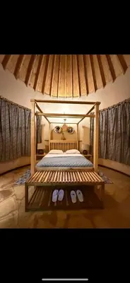a bedroom with a canopy bed with a pair of slippers at The Fort Valley BnB , Karatu in Karatu