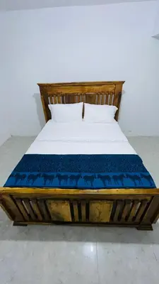 a bed with a wooden frame with a blue mattress at Mount Meru Baraka House