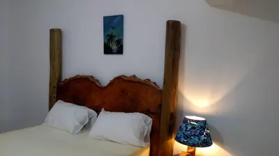 a bed with a wooden headboard next to a lamp at Mount Meru Baraka House