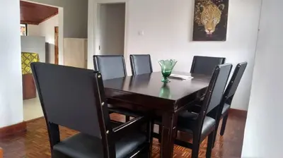 a dining room table with black chairs and a vase on it at Mount Meru Baraka House