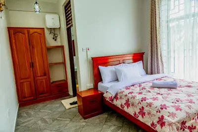 a bedroom with a bed with a red headboard and a window at Bellevie Homestays in Uru