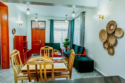 a dining room and living room with a table and chairs at Bellevie Homestays in Uru