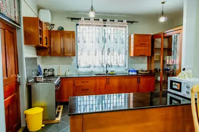 a large kitchen with wooden cabinets and a window at Bellevie Homestays in Uru