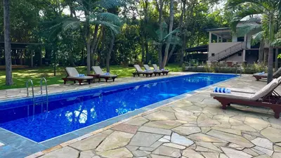 a swimming pool with lounge chairs next to a house at Green Hills Lodge in Usa River