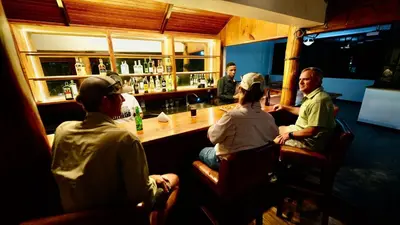 a group of people sitting at a bar at Green Hills Lodge in Usa River