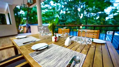 a wooden table with plates and napkins on top at Green Hills Lodge in Usa River