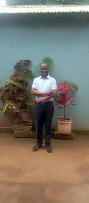 a man standing in front of a wall with plants at Gift Homestay in Karatu