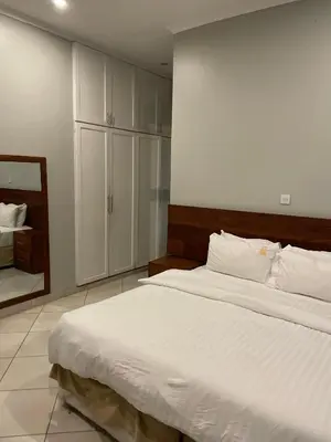 a bedroom with a large white bed and a mirror at Attorney Pad in Arusha