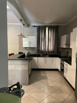 a kitchen with white cabinets and black counter tops at Attorney Pad in Arusha