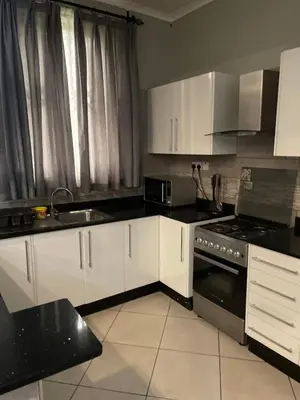 a kitchen with white cabinets and a sink and a stove at Attorney Pad in Arusha