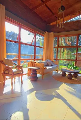 a living room with chairs and a couch and windows at Daima Escape in Usa River