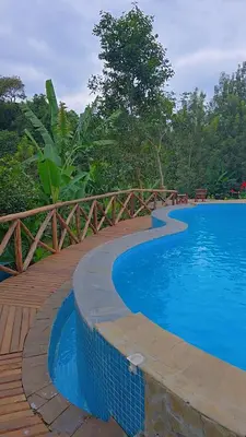 a large swimming pool with a wooden walkway next to a fence at Daima Escape in Usa River