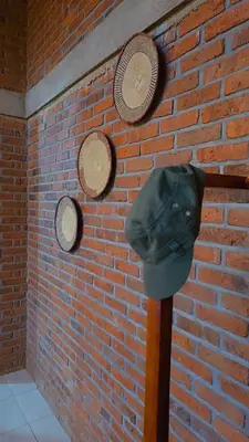 a brick wall with three hats on a wall at Daima Escape in Usa River
