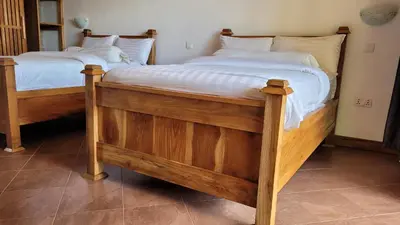 two twin beds in a room with white sheets at Babylon Lodge in Marangu