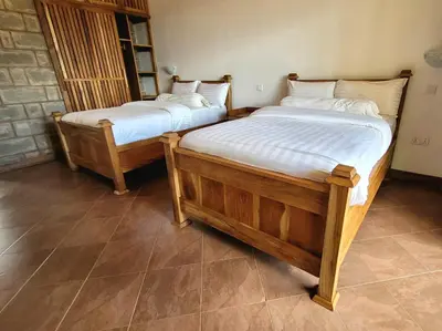two twin beds in a room with tile floors at Babylon Lodge in Marangu