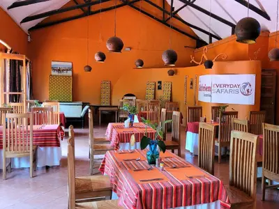 a restaurant with tables and chairs in a room at Babylon Lodge in Marangu