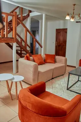 a living room with a couch and a chair and tables at Fusion of Style & Comfort in Arusha