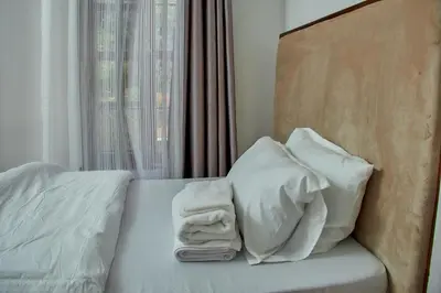 a bed with white sheets and pillows next to a window at Fusion of Style & Comfort in Arusha