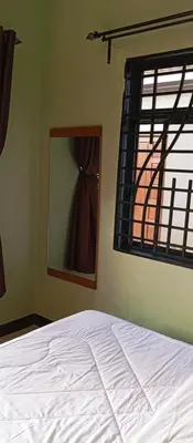 a bedroom with a bed and a mirror and a window at Elwood Lodge in Arusha