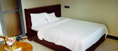 a bedroom with a large bed with white sheets at Elwood Lodge in Arusha