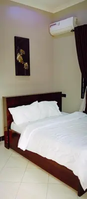 a bedroom with a large bed with white sheets at Elwood Lodge in Arusha
