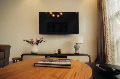 a living room with a table and a tv on the wall at Garden Villa by Wedelia Homes in Tengeru
