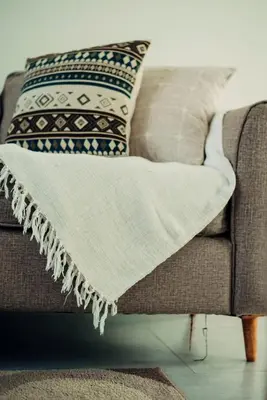 a blanket on a couch with pillows on it at Garden Villa by Wedelia Homes in Tengeru