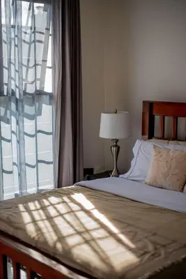 a bedroom with a bed and a large window at Garden Villa by Wedelia Homes in Tengeru