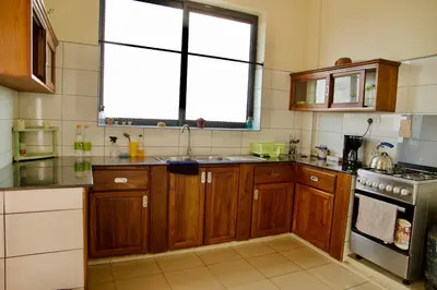 a kitchen with wooden cabinets and a sink and a window at Tai Africa Apartment in Arusha