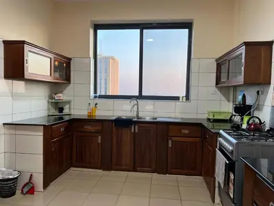 a kitchen with wooden cabinets and a large window at Tai Africa Rooms in Arusha