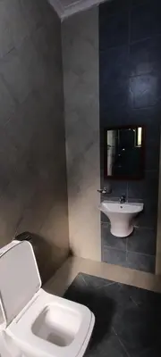 a bathroom with a white toilet and a sink at Nguchiro Palace Hotel in Moshi