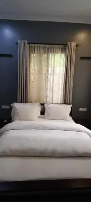 a large bed with white pillows in front of a window at Nguchiro Palace Hotel in Moshi