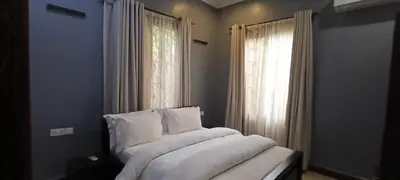 a bedroom with a bed with white sheets and a window at Nguchiro Palace Hotel in Moshi