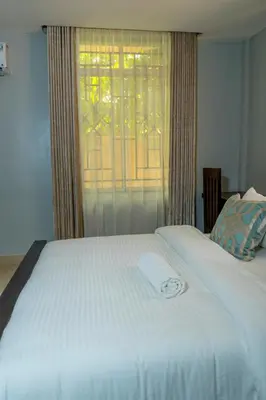 a white bed with a window in a bedroom at Nguchiro Palace Hotel in Moshi