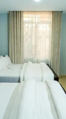 two beds in a room with a window at Nguchiro Palace Hotel in Moshi