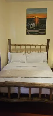 a wooden bed with pillows and a painting on the wall at African Royal Villa and Campsite in Karatu