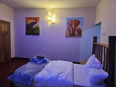 a bedroom with a bed and paintings on the wall at African Royal Villa and Campsite in Karatu